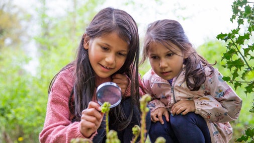 Children look through a magnifying glass at Quarry Bank Mill in Cheshire